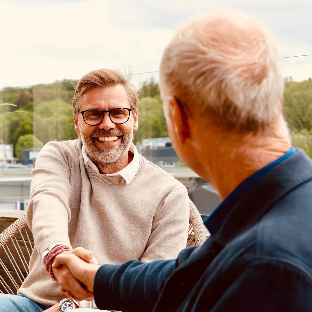 Två personer skakar hand och ler efter ett samtal